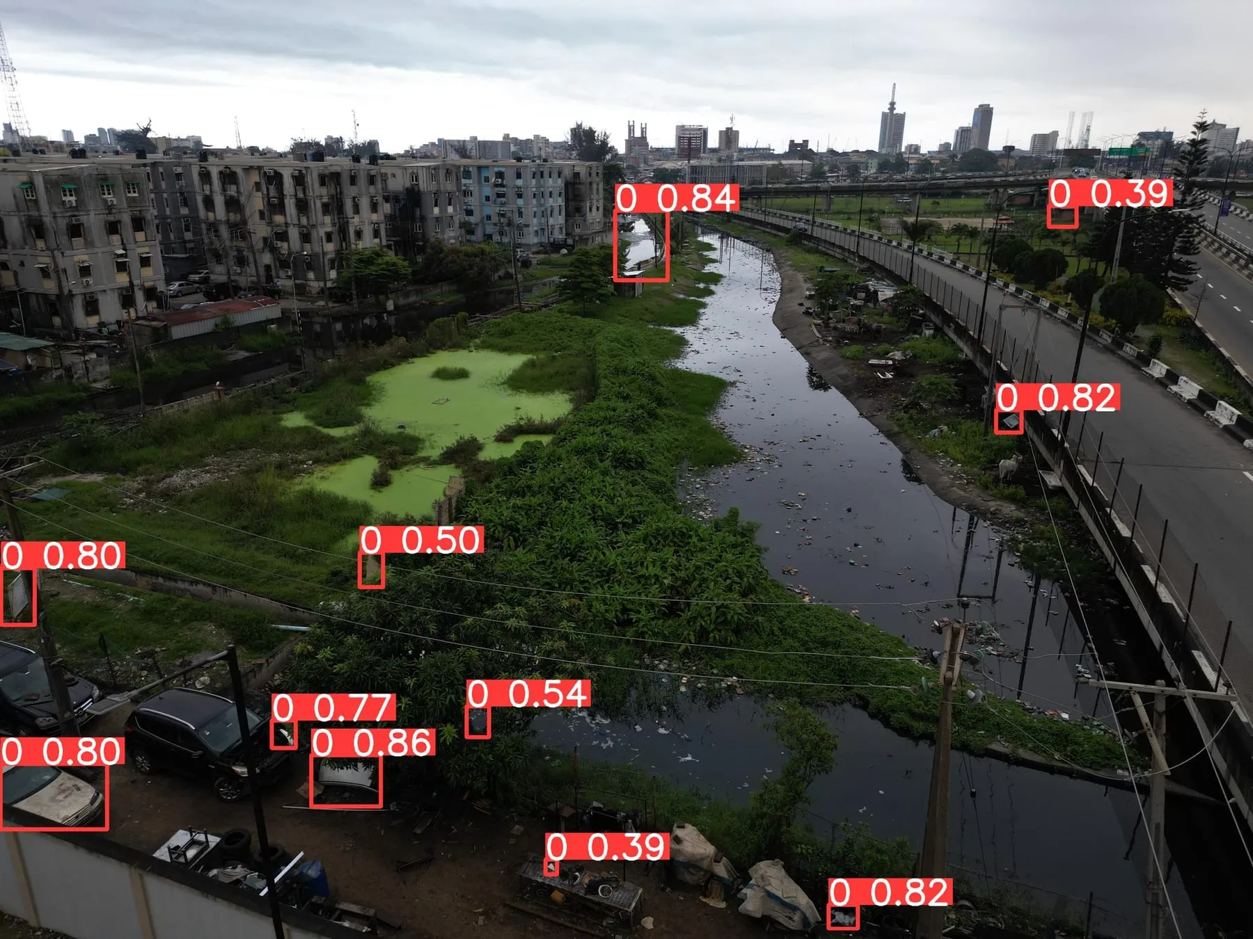 Lagoon channel with floating vegetation and detected plastic along the banks.